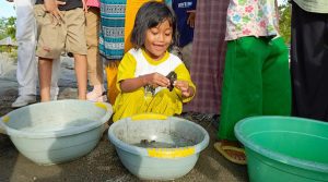 Seorang anak mengangkat seekor tukik saat akan dilepasliarkan ke laut di di Pantai Baturoko, Desa Lalombi, Banawa Selatan, Donggala, Rabu (5/6/2024). (Foto: Iwan)