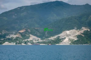 Bentangan perbukitan pesisir yang ditambang untuk material galian C bagi pembangunan Ibu Kota Nusantara (IKN) di pesisir Teluk Palu, Sulawesi Tengah, Kamis (12/6/2025). Data dari Minerba One Map Indonesia (MOMI) Kementerian ESDM, sekitar 30 juta ton batu pecah dipasok dari usaha pertambangan di Sulawesi Tengah untuk pembangunan IKN dan hingga akhir 2024 tercatat 69 izin pertambangan galian C aktif di Kota Palu dan Donggala dengan total luas lahan 1.764,41 hektare. (rindang.ID/Basri Marzuki)