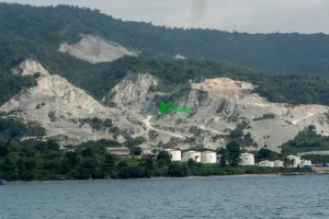 Bentangan perbukitan pesisir yang ditambang untuk material galian C bagi pembangunan Ibu Kota Nusantara (IKN) di pesisir Teluk Palu, Sulawesi Tengah, Kamis (12/6/2025). Data dari Minerba One Map Indonesia (MOMI) Kementerian ESDM, sekitar 30 juta ton batu pecah dipasok dari usaha pertambangan di Sulawesi Tengah untuk pembangunan IKN dan hingga akhir 2024 tercatat 69 izin pertambangan galian C aktif di Kota Palu dan Donggala dengan total luas lahan 1.764,41 hektare. (rindang.ID/Basri Marzuki)